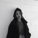 Chinwe standing against a painted brick wall